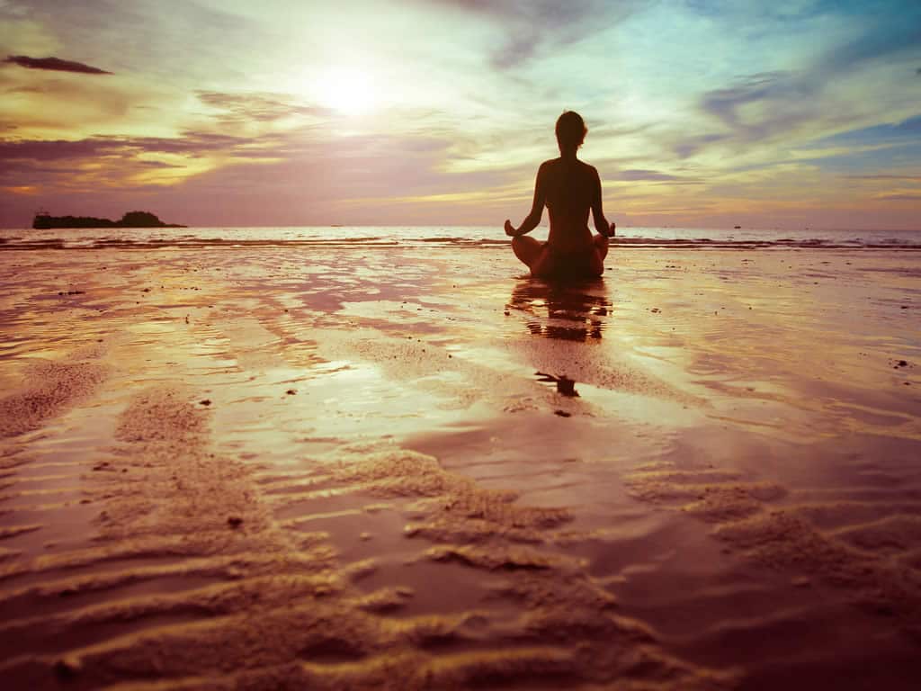 Frau meditiert am Strand